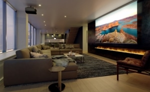 Media room with a projector and large screen. A lit fire feature extends the length of the screen.