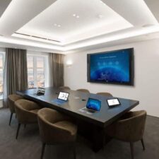 A conference room with a large display and in-ceiling speakers.