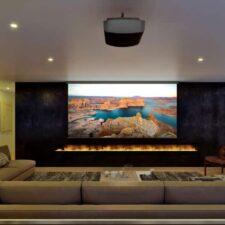 A casual home theater with a Sony projector and large screen above a fire feature.