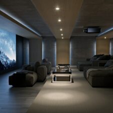 A large home theater with plush seating, a projector, and a large screen with an image of snowy mountains.
